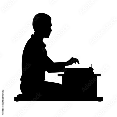 Silhouette of a man sitting on the floor typing on a typewriter