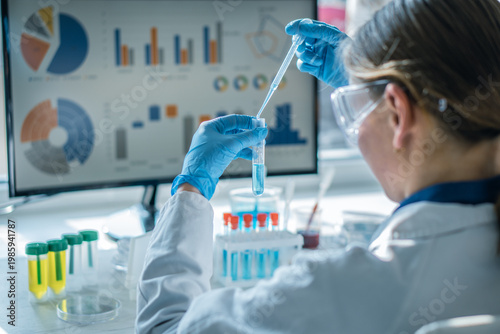 Female researcher in modern laboratory uses pipette to transfer liquid samples, focusing on scientific analysis. Laboratory glassware, digital data visualization highlight advanced research methods
