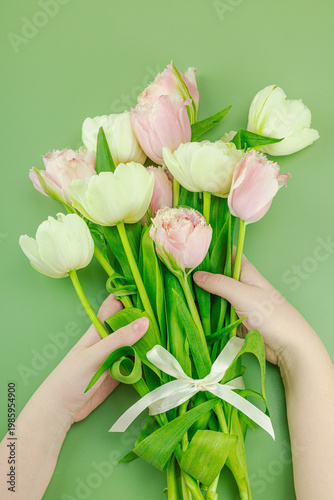 Greeting card concept for Mothers Day. Child's hands holding a bouquet of pink fringed, white tulips