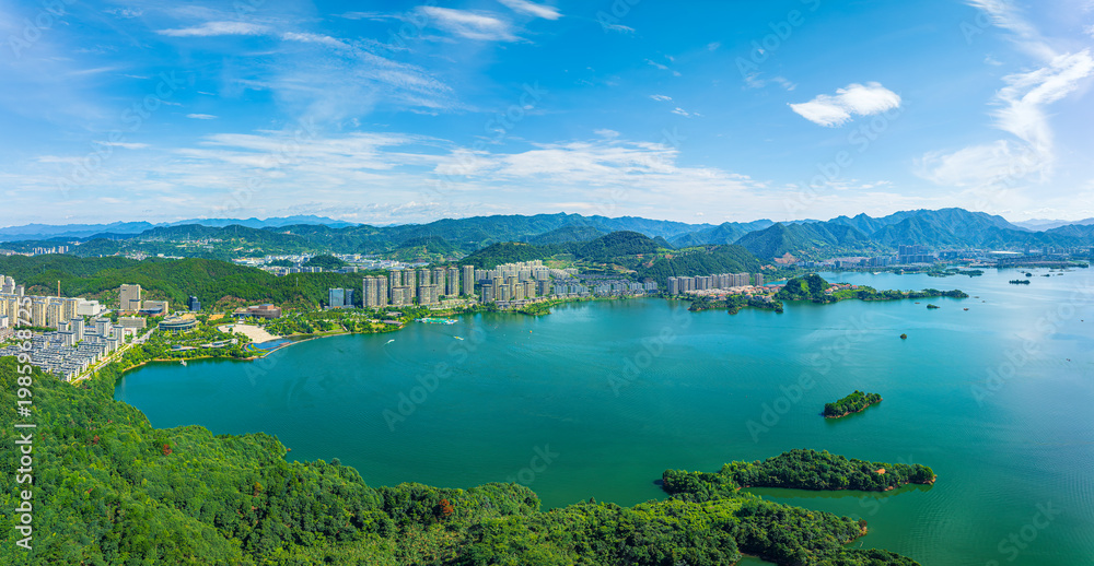 Obraz premium Panoramic aerial view of Qiandao Lake with lush green islands and modern lakeside city buildings in Hangzhou, China.
