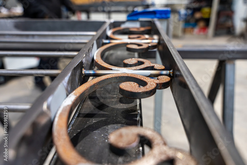 Fotografie Détail de volutes en fer forgé avec points de soudure sur un cadre métallique dans un atelier de ferronnerie d'art