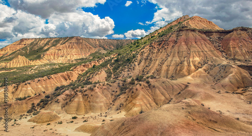 Bardenas desert with its sandstone hills under a blue sky and white clouds