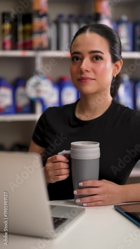 Female entrepreneur talking to a client while holding a mug in her auto parts store