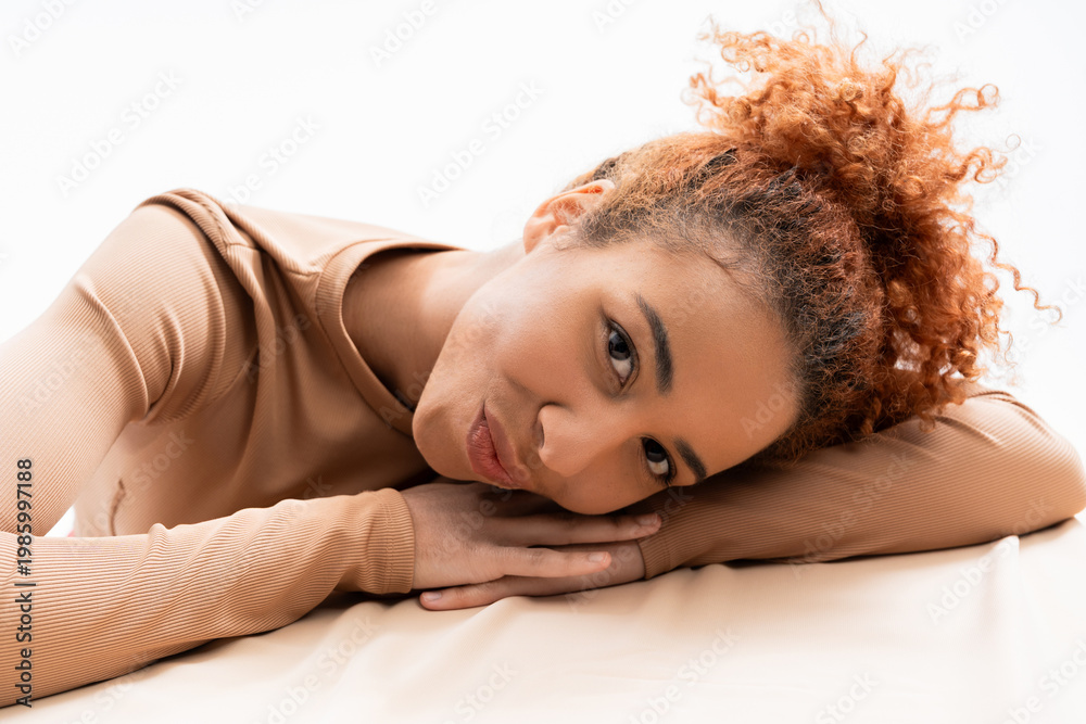 Naklejka premium Beautiful young woman with curly hair enjoying a moment of serenity in a soft, cozy space