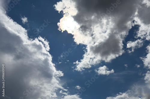 Clouds part to reveal sunlight and blue sky after storm. Bright clearing shows transition from dark weather to calm atmosphere. Concept of nature renewal change..
