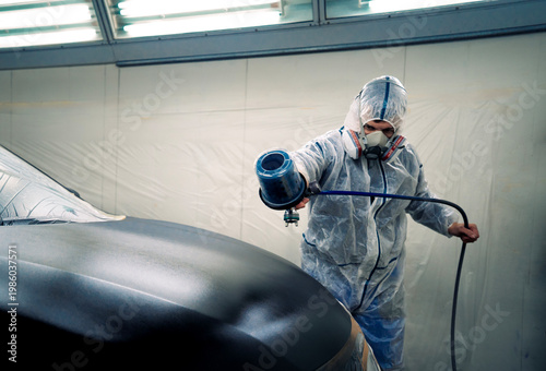 Obraz na płótnie Pintor profesional aplicando pintura a un coche en una cabina especializada