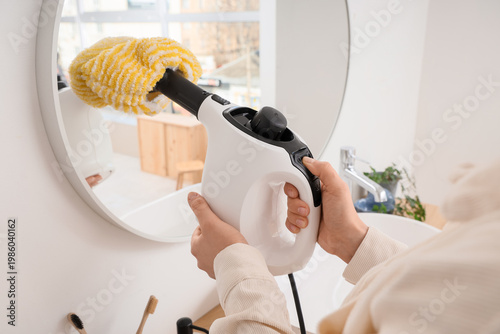 Woman steam cleaning mirror...