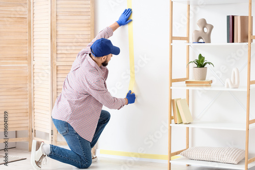 Young male decorator applyi...