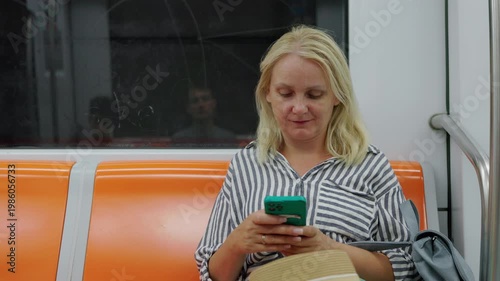 Woman using smartphone while sitting in subway train, urban commute and modern lifestyle concept