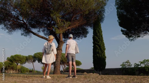 Couple exploring Appia Antica Park Rome looking at pine tree in warm sunset light with ancient landscape