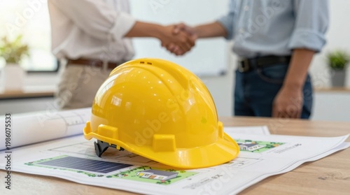 Contract signing between construction professionals in an office setting with hard hat on table