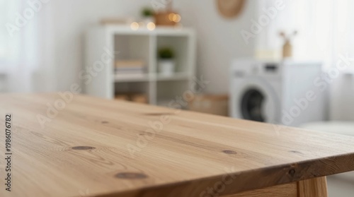 Wooden table in a bright room with a washing machine and shelving units in the background