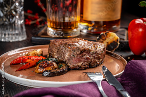 Juicy grilled beef steak with vegetables and whiskey