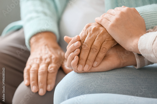 Foto Senior woman with daughter holding hands at home, closeup
