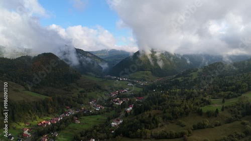 Aerial view of mountain village in green valley under cloudy sky