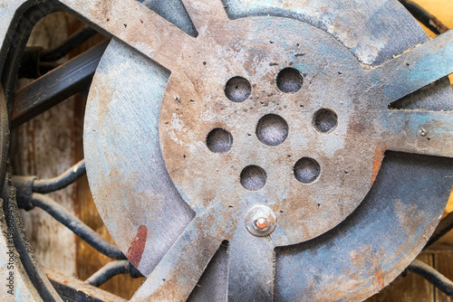 Extreme close up of a rusted metal film reel with circular holes and weathered texture.