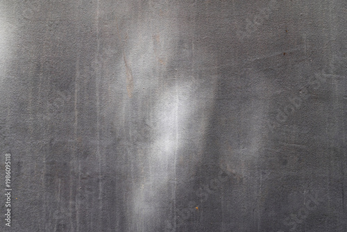 Dark gray plastered wall with subtle vertical streaks and light spots.