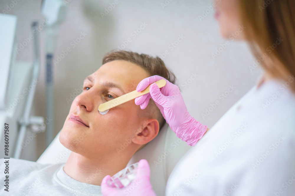 Naklejka premium Male cosmetics. Good looking man receiving face treatment at luxury spa