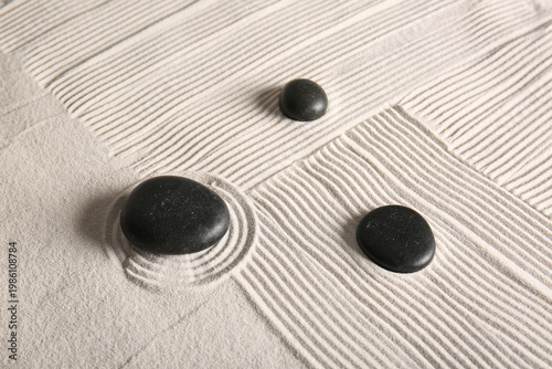 Photography Black stones on sand with pattern. Zen concept