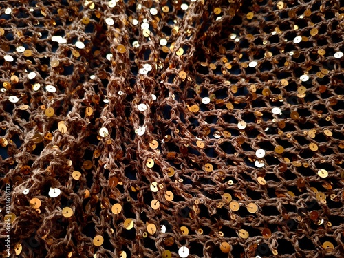 Luxurious brown mesh fabric with gold and silver sequins, shiny textured background for fashion and design, macro detail of glittery netting
