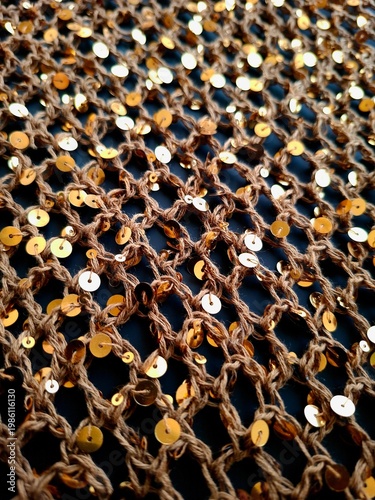 Brown sequined mesh fabric texture with gold and silver sparkles, luxury fashion textile background, close-up of shiny netting material
