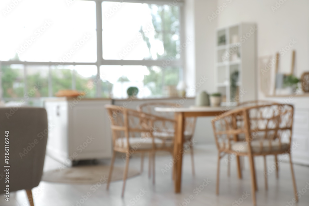 Fototapeta premium Blurred view of light kitchen with counters and dining table