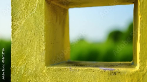 A close-up view of a bright yellow window frame with clean glass and ornate details