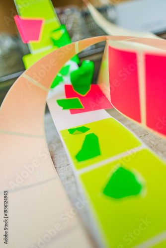 Bright coloured Illuminous adhesive label rolls on an industrial production line in packaging and manufacturing environment. Food labels for health safety and hygiene purposes.