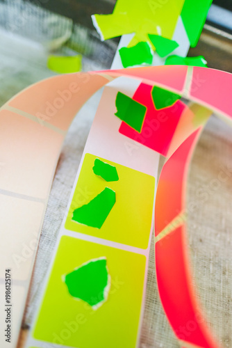 Bright coloured Illuminous adhesive label rolls on an industrial production line in packaging and manufacturing environment. Food labels for health safety and hygiene purposes.