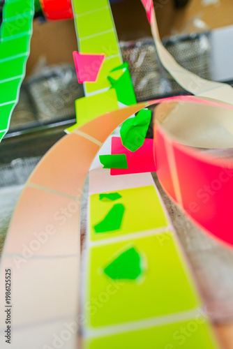 Bright coloured Illuminous adhesive label rolls on an industrial production line in packaging and manufacturing environment. Food labels for health safety and hygiene purposes.