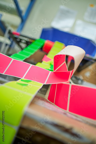 Bright coloured Illuminous adhesive label rolls on an industrial production line in packaging and manufacturing environment. Food labels for health safety and hygiene purposes.