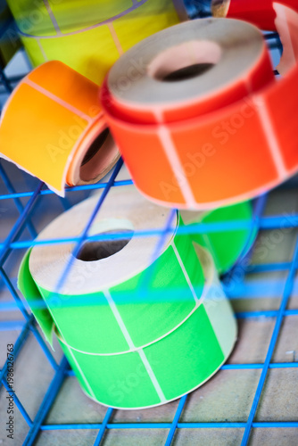 Bright coloured Illuminous adhesive label rolls on an industrial production line in packaging and manufacturing environment. Food labels for health safety and hygiene purposes.