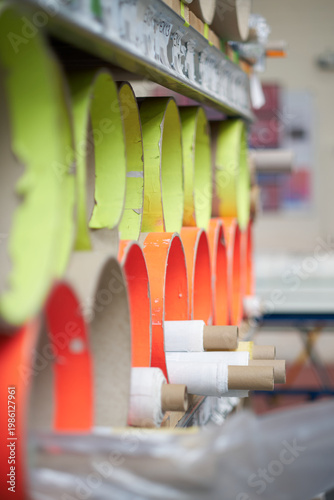 rows of material cardboard rolls and cardboard cores stored on industrial rack in textile and manufacturing workspace. Fabric and manufacturing textile storage.