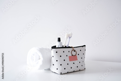 Photos A stylish polka-dot toiletry bag with a pink label and keyring holds two toothbrushes and a tube of toothpaste