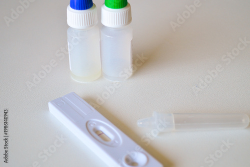 Close up of a rapid medical diagnostic test kit with reagent bottles and an extraction tube on a white surface for healthcare screening and virus detection.