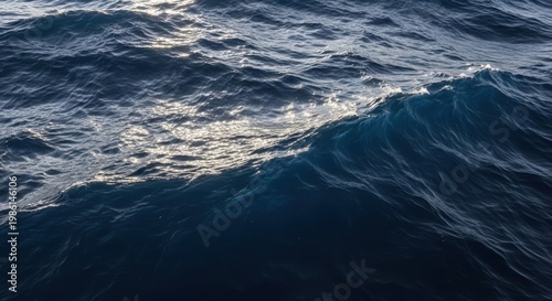 Dark blue ocean waves with sunlight reflecting on the surface of water