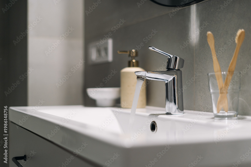 Fototapeta premium Modern bathroom sink with running water from open faucet