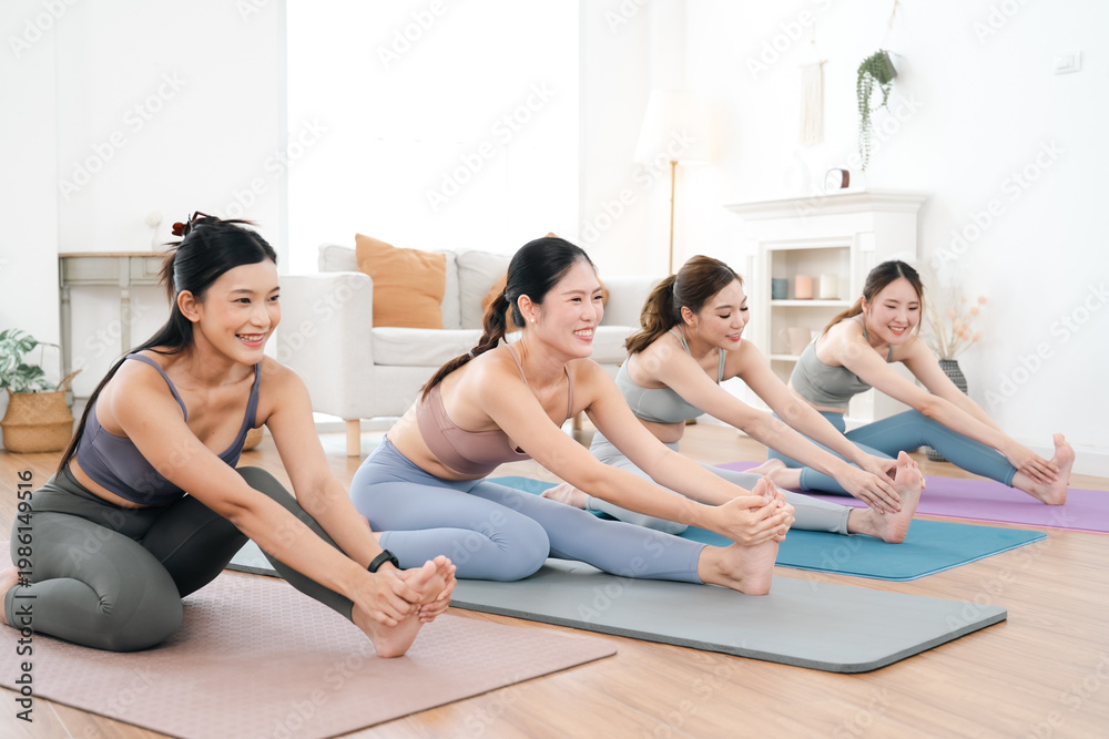 Obraz premium Wellness pilates yoga woman exercise stretching Four women doing wellness pilates yoga stretching mat bright living room studio smiling during group workout for flexibility balance and healthy