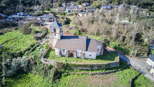 Aerial view of the church of Our Lady of the Assumption, belonging to the parish of San Juan de Paluezas, standing out imposingly on a barbican at the top of the Bierzo village
