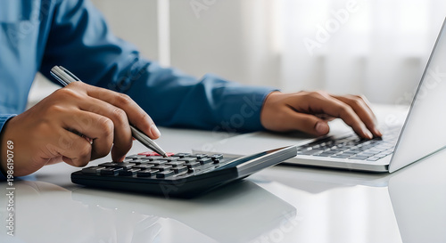 Close-up of hands using a calculator and typing on a laptop keyboard, symbolizing financial planning and accounting