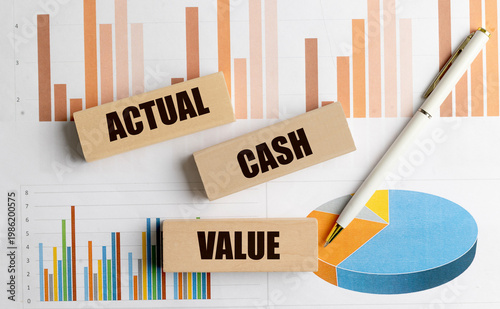 Actual cash value text on wooden blocks with pen and financial charts on desk business finance concept