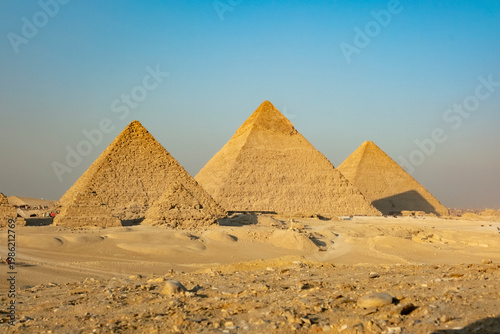 View of pyramids in Giza during sunset with clear sky and desert landscape in the background