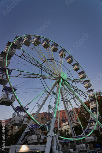 Illuminated Ferris wheel in front of a mountain in the evening in the city center of Makarska on the Riviera in Dalmatia, in late summer.