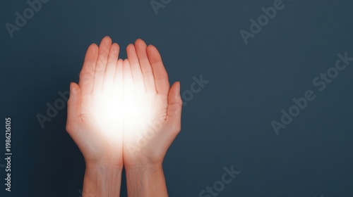 Social justice visual concept, Two hands cupping a glowing white light against a dark background, symbolizing care, energy, or protection.