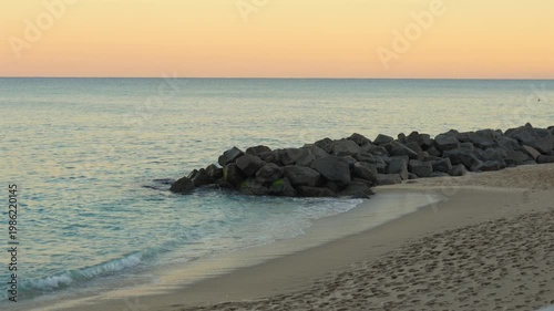 Calm beach with gentle waves and sunset coastal scene