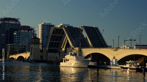 Sunlit drawbridge closing with boats and calm reflections