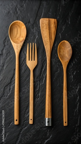 Wooden kitchen utensils including spoons and spatula arranged on dark slate
