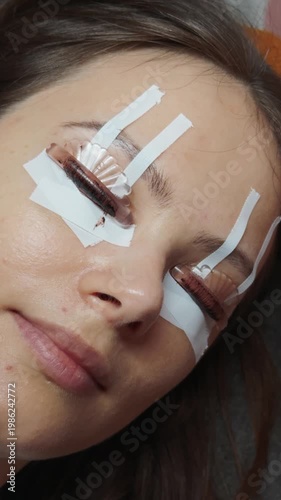 Woman receiving professional eyelash lift in a beauty studio, specialist applying solution to lift and shape natural lashes for a defined, semi permanent open eye look and self care