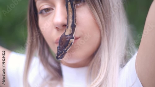 Young woman holding python snake portrait closeup, wild nature concept