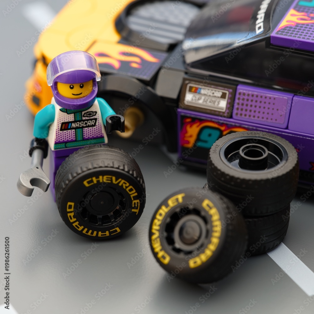 Fototapeta premium Tambov, Russian Federation - January 17, 2026 Lego driver minifigure changing wheel of a Lego NASCAR Next Gen Chevrolet Camaro ZL car.